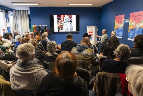 Le public assis dans une salle de la Micro-Folie face à un écran, lors d’une rencontre.